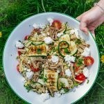 Ingrediënten voor orzo salade: oesterzwammen, courgette, cherrytomaatjes, feta, peterselie, citroen en kruiden op een aanrecht